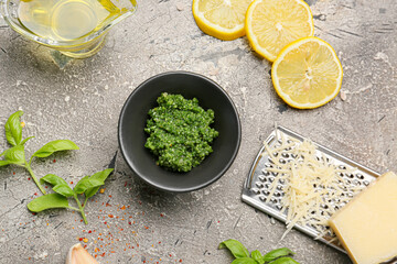 Bowl of tasty pesto sauce and ingredients on grey background