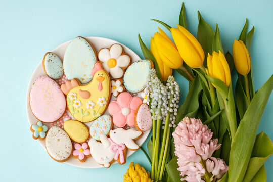 Easter greeting card with fresh tulip flowers, Gingerbread cookies - Easter eggs, chocken hen, bunny and flowers on white plate, top view with copy space, homemade sweets for spring party