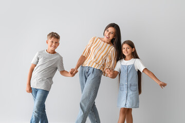 Fototapeta premium Happy dancing woman and her children on light background