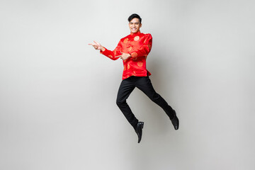 Portrait of smiling handsome Asian man in traditional chinese attire smiling and pointing hands to empty space aside in light gray isolated studio background