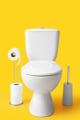 Toilet bowl, brush and holder with roll of paper on yellow background
