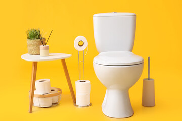 Holder with rolls of paper, toilet bowl and table on color background