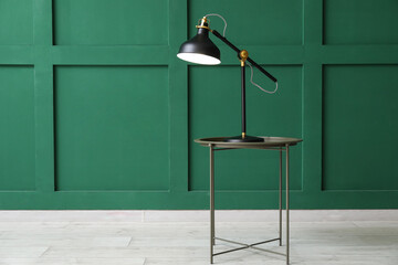 Glowing black lamp on table near green wall