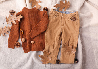 Baby clothes and autumn decor on fabric background