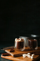 Glasses of natural hot chocolate with marshmallows on black background