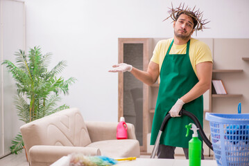 Young male contractor wearing prickly wreath on head cleaning th