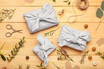 Composition with gift boxes wrapped in fabric, scissors and decor on wooden background