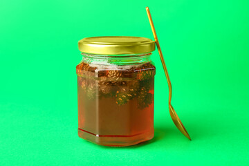 Jar of tasty pine cone jam on green background