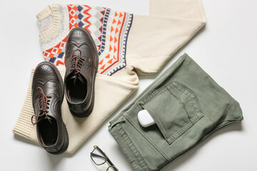 Male clothes, shoes, eyeglasses and earphones on light background