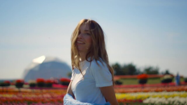 Beautiful girl dancing in flower garden. Young lady feeling joy in spring park.