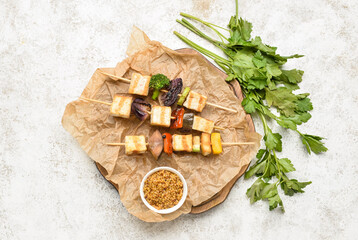 Board with grilled tofu cheese skewers and mustard on light background
