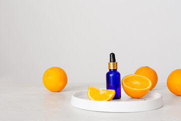 Bottle of essential oil and fresh orange on light background