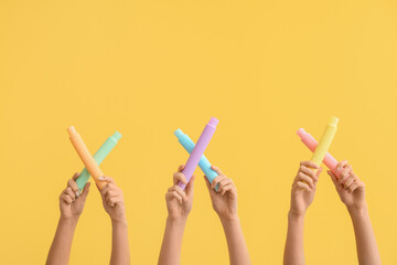 Hands with popular pop tubes on color background