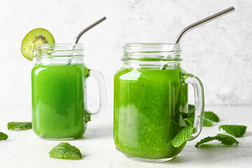 Mason jars of healthy green juice on light background