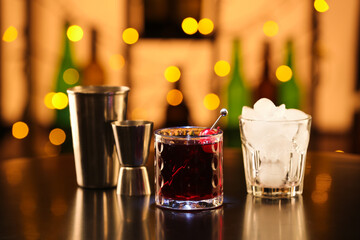 Glass of tasty Manhattan cocktail with ice on table in bar