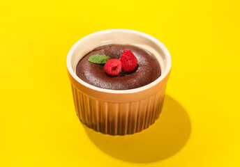 Ramekin with tasty lava cake fondant and raspberry on yellow background