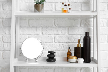Shelf with bath supplies near white brick wall