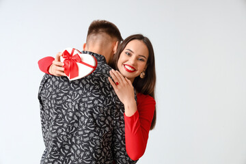 Happy couple with gift on light background. Valentine's Day celebration