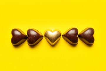 Tasty heart-shaped candies on yellow background
