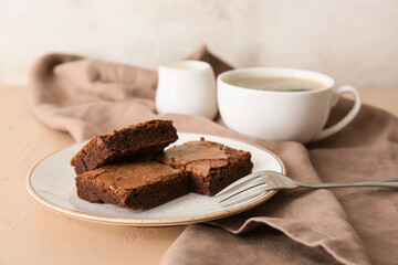 Plate with pieces of tasty chocolate brownie on beige background