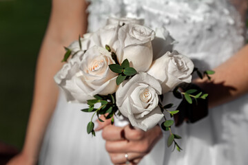 Bride holding wedding bouquet, flowers of white roses