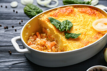 Baking dish with tasty English fish pie on black wooden background