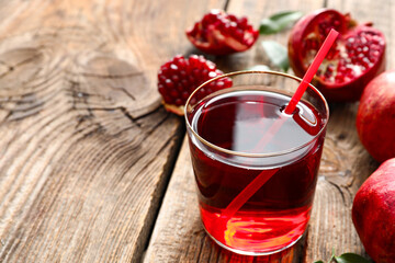 Glass of delicious pomegranate juice on wooden background