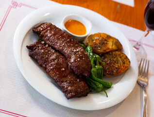 Grilled beef fillet with side dish of crispy baked potato in skin, green peppers and Argentinian chimichurri sauce