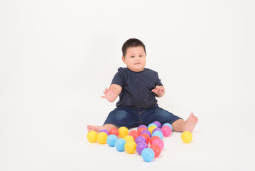 portrait of cute adorable little boy is sitting and playing colorful balls on white background studio