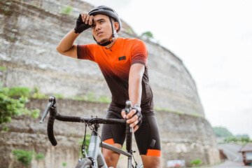 male cyclist feeling tired and wipe his sweat - Powered by Adobe