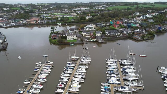 Aerial view of Kinsale harbour and bay, Ireland, moored sailboats anc colorful buildings on riverbanks - drone shot