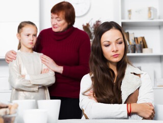 Fototapeta premium Portrait of young mother upset after quarrel with little daughter standing behind with grandma