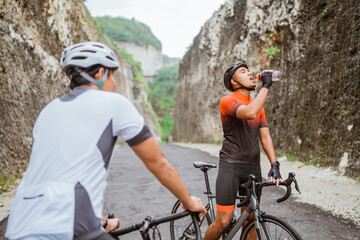 Obraz premium road bike cyclist take a brake and drink a bottle of water