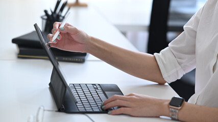 Cropped shot businesswoman holding stylus pen pointing on screen of computer tablet.