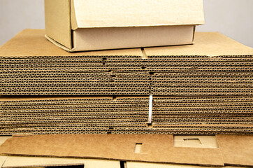 box ready for product packaging and a stack of folded corrugated cardboard sheets on a table.