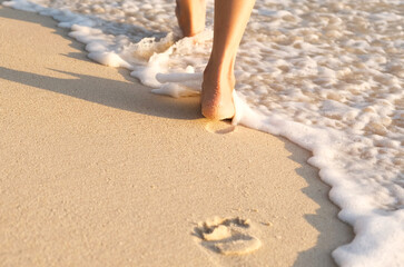 woman walking to sea and beach on a beautiful island Ocean foam wrapped around a girl's leg. Walking in the early morning sunshine to get natural vitamin D