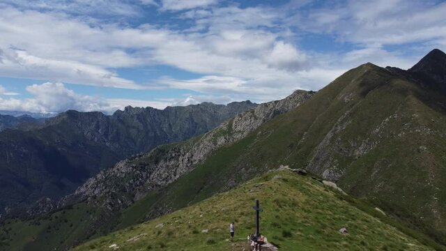 Panoramic shot of people that reached the cross at the mountaintop - Lake Lago Maggiore - North of Italy. Aerial shot with drone with fly-over motion