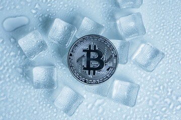 Obraz na płótnie Canvas Bitcoin coin middle melting ice cubes and water drops on light background.