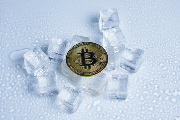 Obraz na płótnie Canvas Bitcoin coin middle melting ice cubes and water drops on light background.