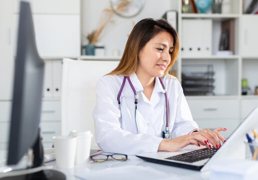 Portrait of latino female doctor working on laptop consulting patient online, telemedicine concept