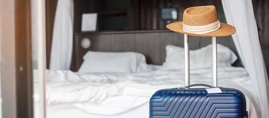 Blue Luggage with hat in modern hotel room after door opening. Time to travel, service, journey,...
