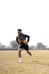 Young Indian boy exercising and jumping on the sports field. Sports and healthy lifestyle concept.