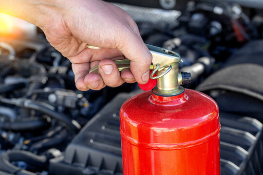 Car Fire Extinguisher On The Background Of The Car Engine. Extinguishing Class Of Fire Extinguisher, Expiration Date. Copy Space For Text