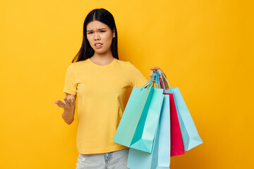 woman with Asian appearance in a yellow T-shirt with multicolored shopping bags studio model unaltered