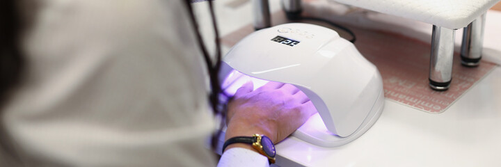 Lady drying gel in ultraviolet lamp