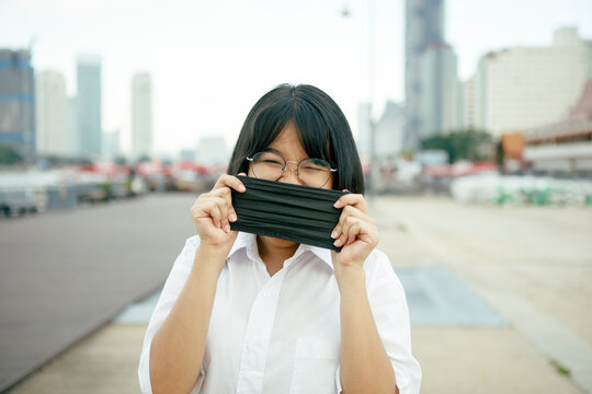 asian teenager with protection face mask in hand standing outdoor