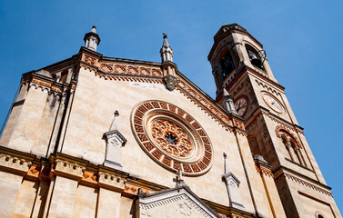 Facade of an old church with a belfry, a rose window and a clock on the tower