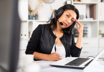 Portrait of tired hispanic female customer service agent during daily work at call center