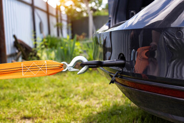 Screws in a tow hook in the car and an orange tow rope for towing, close-up, industrial