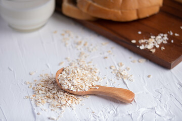 Obraz na płótnie Canvas oatmeal in wooden spoon and fresh milk on white background healthy food